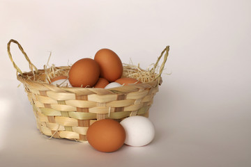 Easter basket, next to it are two chicken eggs. Close-up. A wicker basket filled with chicken eggs.