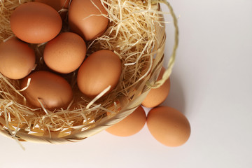 Easter basket on its side. Brown eggs in a basket on a straw, next to the basket are eggs. A wicker basket filled with chicken eggs.