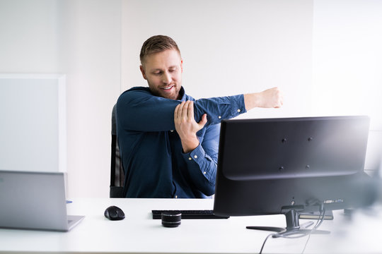 Close-up Of Businessman Stretching His Hands At Workplace