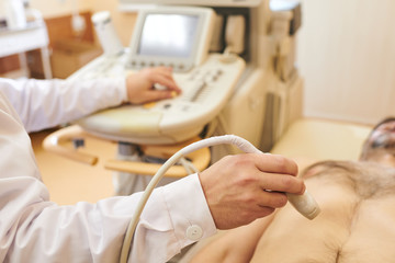 Close-up of unrecognizable sonographer using ultrasound probe while checking belly of patient