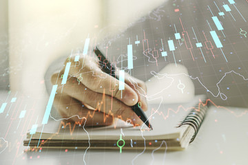 Multi exposure of abstract creative financial chart with world map and with man hand writing in notebook on background, research and analytics concept
