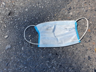 Incorrectly used disposable surgical masks on the road.The correct way to get rid of a protective mask is to fold and tie in a plastic bag before throwing it in trash to prevent the spread  Covid-19.