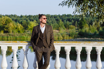Obraz premium Fashionable guy in a suit and sunglasses on the pier