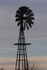 windmill in the sunset with clouds in Kansas.