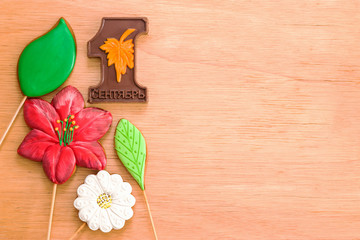 Gingerbread, cookies in the form of a leaf flower, chocolate number 1C with the inscription September. Theme back to school, blank for a postcard. Beige wooden background with a copy of the space