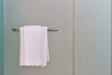 A towel hanging on a bar attached to frosted film glass partition in shower room. Concept image for hotel hygiene. 