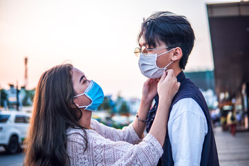 Young millennials couple hugging and wearing a protective face mask, virus spread prevention and people concept