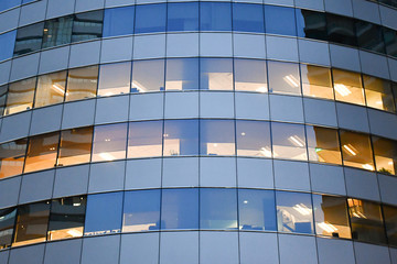 Fototapeta na wymiar Concept image for hard work and late at night office, Office light in evening, Frameless glass wall modern office building exterior facade