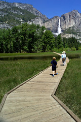 A great Adventure! Grandson following grandparents crossing Sentinel Meadow on wood-plank path with...
