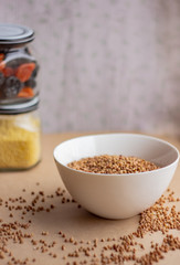 Dry buckwheat in white ceramic bowls, ingredients for making breakfast or lunch