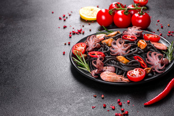Black seafood pasta with shrimp, octopus and mussels on black background. Mediterranean gourmet food