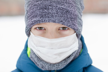 The danger of coronavirus. A boy on a walk walks in a medical mask on his face