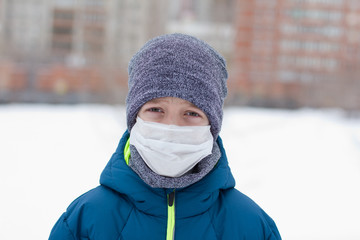 The danger of coronavirus. A boy on a walk walks in a medical mask on his face