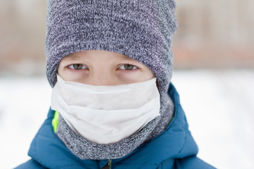 The danger of coronavirus. A boy on a walk walks in a medical mask on his face
