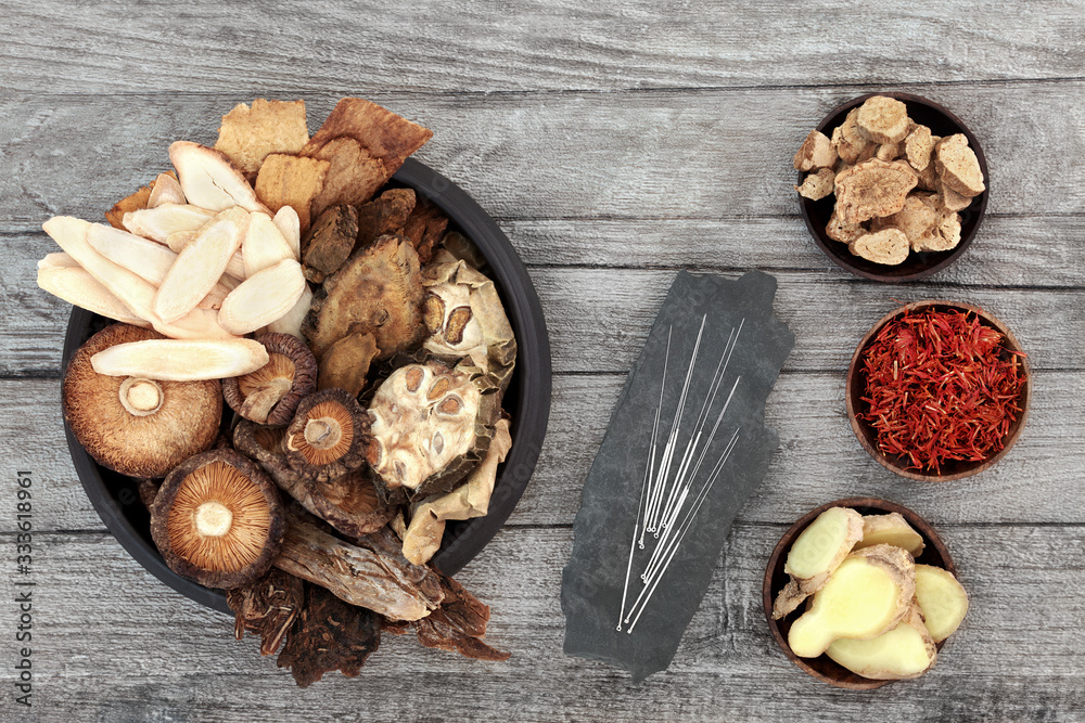 Sticker chinese herbs and acupuncture needles used in traditional herbal medicine on rustic wood background.