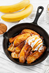 Homemade fried bananas foster with cinnamon and ice cream in cast iron pan