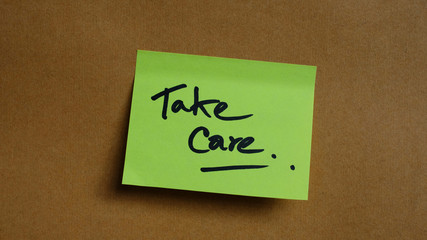 green sticker on brown background. motivational, quote, and words, note, message 'take care'