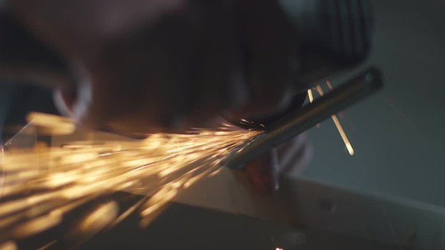 Industrial worker using angle grinder and cutting steel working in industrial factory. Man works in a plant. Instrument in industry. Equipment in production workshop. Slow Motion. Close up.