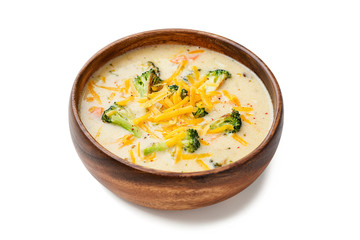 Wooden bowl of creamy broccoli cheddar cheese soup isolated on white background