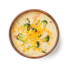 Wooden bowl of creamy broccoli cheddar cheese soup isolated on white background