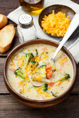 Wooden bowl of creamy broccoli cheddar cheese soup with toasted  bread