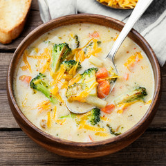 Wooden bowl of creamy broccoli cheddar cheese soup with toasted  bread