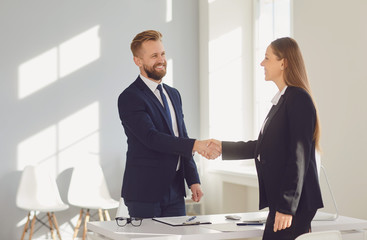 Successful office interview. The conclusion of the contract. Businessman and businesswoman handshake at the table after meeting.