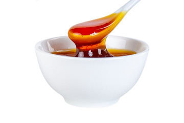 honey dripping from ceramic spoon to ceramic bowl