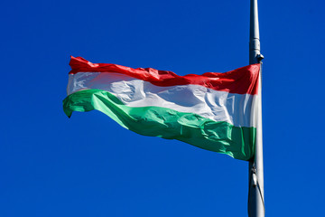 Hungarian national flag blowing in the wind in direct sunlight towards clear blue sky in a sunny day