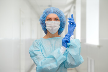 Fototapeta na wymiar Portrait of doctor in scrubs. A female doctor in a protective cap and face mask in safety measures against the coronavirus.