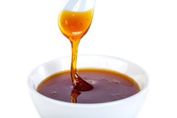 honey dripping from ceramic spoon to ceramic bowl