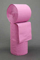 Pyramid of rolls of pink toilet paper on a dark grey background. Space for text