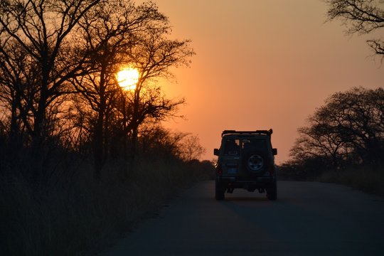 Silhouette of a well equipped four wheel drive off road vehicle driving into the bushveld sunset in Kruger National Park in South Africa