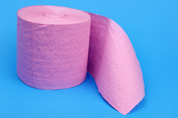 Roll of pink toilet paper on bright blue background. Space for text