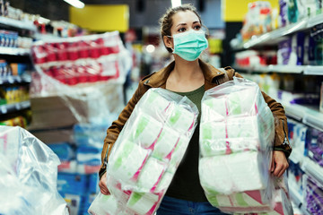 Woman with face mask buying toilet paper in supermarket during virus epidemic. © Drazen