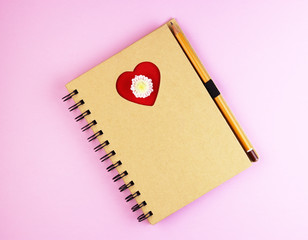a love heart on a Notepad with a pen on a blue wooden table