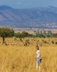 Naklejka premium Young woman enjoying a walking safari in Uganda, Africa, with giraffes in the background.