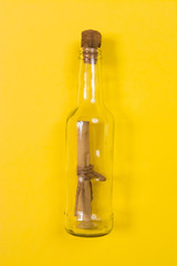 Message in bottle on yellow background with copy space for text