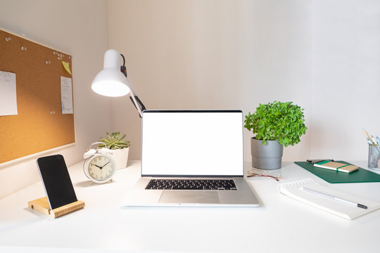 Laptop with blank white screen on office desk interior. Stylish rose gold workplace mockup table view. 