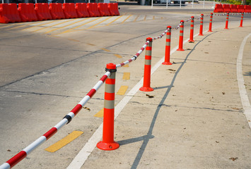 Orange traffic poles and plastic tube in red and white are setting up for road side protection.