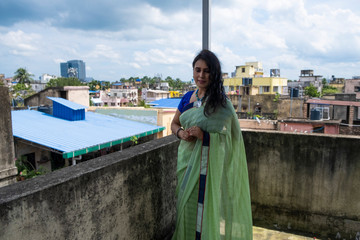 Portrait of a beautiful smiling brunette Indian Bengali woman in traditional wear sari standing on...