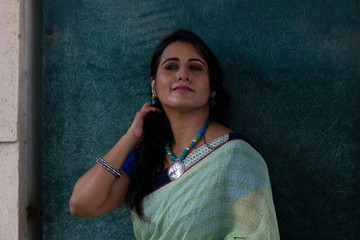Portrait of a beautiful smiling brunette Indian Bengali woman in traditional wear sari posing on...