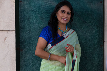 Portrait of a beautiful smiling brunette Indian Bengali woman in traditional wear sari posing on...