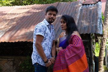 A brunette Indian Bengali romantic couple in traditional wear interacting between themselves in the...