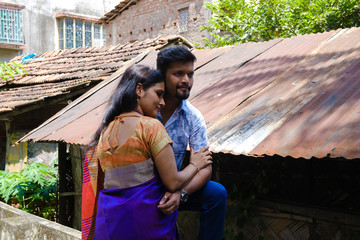 A brunette Indian Bengali romantic couple in traditional wear interacting between themselves in the street in the morning of Durga Puja festival in urban background. Indian lifestyle.