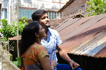 A brunette Indian Bengali romantic couple in traditional wear interacting between themselves in the...