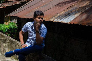 Portrait of a handsome brunette Indian bengali smart man in shirt and trousers sitting in front of...