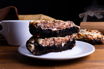 Delicious cookie cakes with chocolate and cheesecake with a cup of coffee on a wooden board with copy space