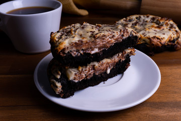 Delicious cookie cakes with chocolate and cheesecake with a cup of coffee on a wooden board with copy space