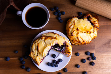 Delicious cheesecake cookie cakes with blueberries and a cup of coffee on a wooden board with copy space